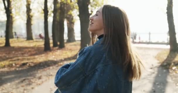 Sígueme, joven chica feliz y olorosa corriendo y pidiéndote que la sigas en el parque amarillo de otoño. Joven mujer atractiva correr y sonreír en los rayos del sol — Vídeo de stock