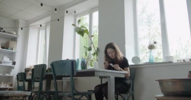 Kadın oyuncak bebek seramik parçası yapıyor. Kadın evde oturuyor ve masada bebek için kulak yapıyor. Çömlek bebekleri parçaları, el yapımı ve yaratıcı yetenekler