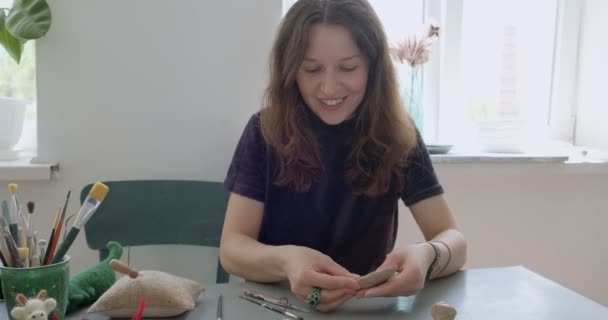 Een vrouw die poppenkeramiek maakt. Vrouwelijk zitten en het maken van oor voor pop thuis aan tafel. Aardewerk poppen onderdelen, handgemaakte en creatieve vaardigheden — Stockvideo