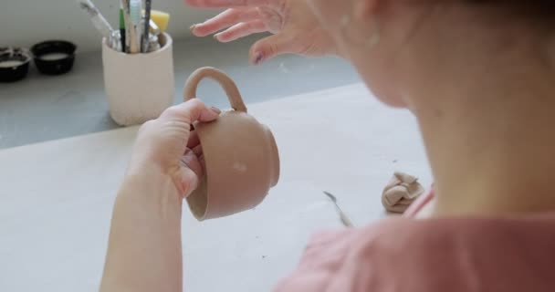 Female potter sitting and makes a cup at the table. Woman making ceramic item. Pottery working, handmade and creative skills — Stock Video