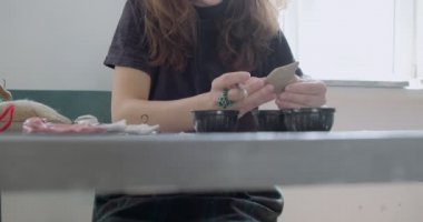 Kadın oyuncak bebek seramik parçası yapıyor. Kadın evde oturuyor ve masada bebek için kulak yapıyor. Çömlek bebekleri parçaları, el yapımı ve yaratıcı yetenekler