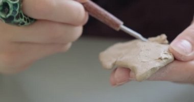 Kadın oyuncak bebek seramiği yapıyor. Kadın evde oturuyor ve masada bebek için kulak yapıyor. Çömlek bebekleri parçaları, el yapımı ve yaratıcı yetenekler