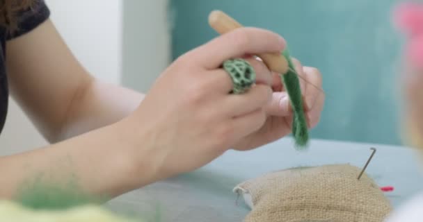 Egy nő gyapjú játékszert készít az asztalnál, közelről. Nő ül, és létre tölgyfa baba otthon. Tű Felted Kézzel készített és kreatív készségek — Stock videók
