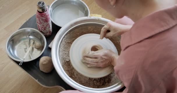 여성 도공이 앉아서 도기 바퀴 위에 컵을 만듭니다. 도자기 제품을 만드는 여성. 일하는 도기, 수제품 및 창조 기술 — 비디오
