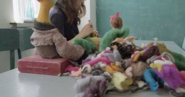 Masada yün oyuncak bebek yapan bir kadın. Kadın evde oturup meşe bebek yapıyor. İğne Keçeli El yapımı ve yaratıcı yetenekler