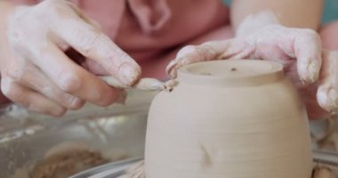 Kadın çömlekçi oturuyor ve çömlek çarkında bir fincan yapıyor. Kadın seramik bir şey yapıyor. Çömlekçilik, el yapımı ve yaratıcı beceriler