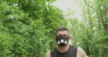 Spor Giyim Maskeli Genç Erkek Ormanda Yolda Koşuyor. Erkekler yoğun idman yapıyor.