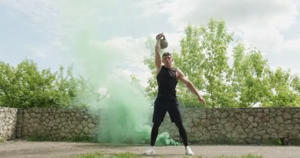 Entrenamiento con pesas, ejercicio intenso de fuerza al aire libre con fondo de humo. Los hombres haciendo ejercicio con kettlebell — Vídeos de Stock