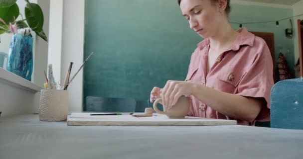 Female potter sitting and makes a cup at the table. Woman making ceramic item. Pottery working, handmade and creative skills — Stock Video