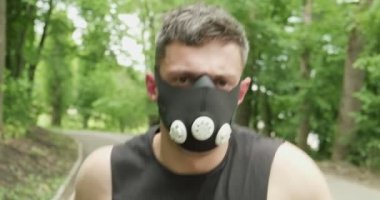 Spor Giyim Maskeli Genç Erkek Ormanda Yolda Koşuyor. Erkekler yoğun idman yapıyor.