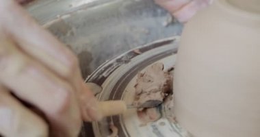 Kadın çömlekçi oturuyor ve çömlek çarkında bir fincan yapıyor. Kadın seramik bir şey yapıyor. Çömlekçilik, el yapımı ve yaratıcı beceriler