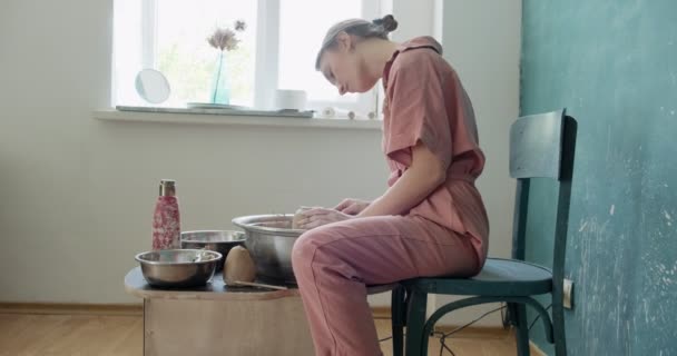 Kvinnlig krukmakare sitter och gör en kopp på keramik hjulet. Kvinna gör keramiska objekt. Keramik arbete, handgjorda och kreativa färdigheter — Stockvideo