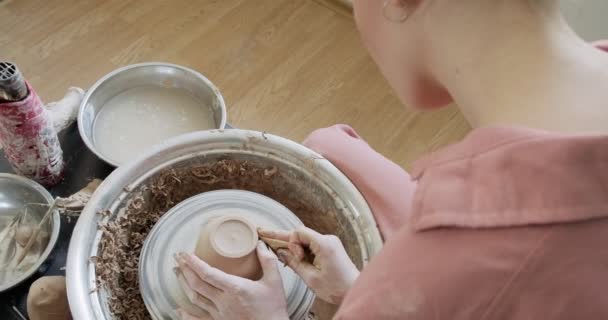 Kvinnlig krukmakare sitter och gör en kopp på keramik hjulet. Kvinna gör keramiska objekt. Keramik arbete, handgjorda och kreativa färdigheter — Stockvideo
