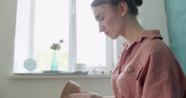 Pembuat tembikar wanita duduk dan membuat cangkir. Wanita membuat barang keramik. Tembikar bekerja, buatan tangan dan keterampilan kreatif — Stok Video