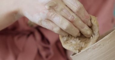 Dişi çömlekçi oturuyor ve bir fincan yapıyor. Kadın seramik bir şey yapıyor. Çömlekçilik, el yapımı ve yaratıcı beceriler