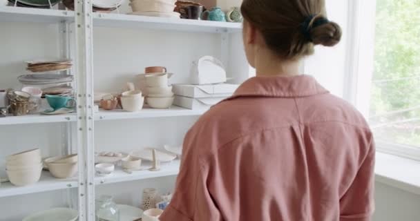 Γυναίκα αγγειοπλάστη εξετάζει πήλινο προϊόν. Γυναίκα που φτιάχνει κεραμικά αντικείμενα. Εργασίες αγγειοπλαστικής, χειροποίητες και δημιουργικές δεξιότητες — Αρχείο Βίντεο