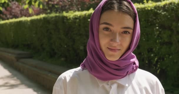 Hermosa mujer joven mirando a la cámara, con el tradicional pañuelo para la cabeza. Atractiva hembra en hijab — Vídeos de Stock