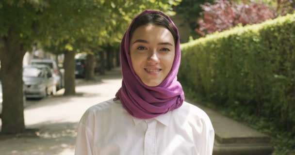 Hermosa joven caminata por la calle, con el tradicional pañuelo en la cabeza. Atractiva hembra en hijab — Vídeos de Stock