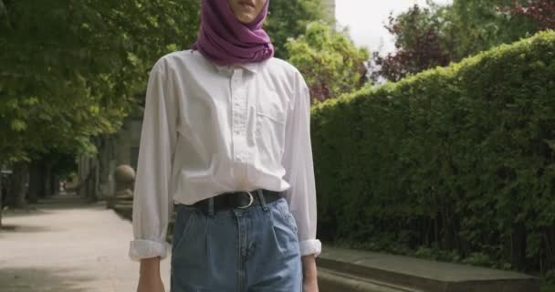 Kaunis nuori nainen kävelee kadulla, yllään perinteinen huivi. Houkutteleva nainen hijabissa — kuvapankkivideo