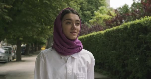 Hermosa joven caminata por la calle, con el tradicional pañuelo en la cabeza. Atractiva hembra en hijab — Vídeos de Stock