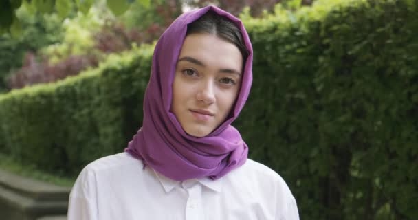 Hermosa mujer joven mirando a la cámara, con el tradicional pañuelo para la cabeza. Atractiva hembra en hijab — Vídeos de Stock