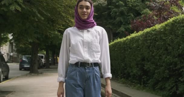 Hermosa joven caminata por la calle, con el tradicional pañuelo en la cabeza. Atractiva hembra en hijab — Vídeos de Stock