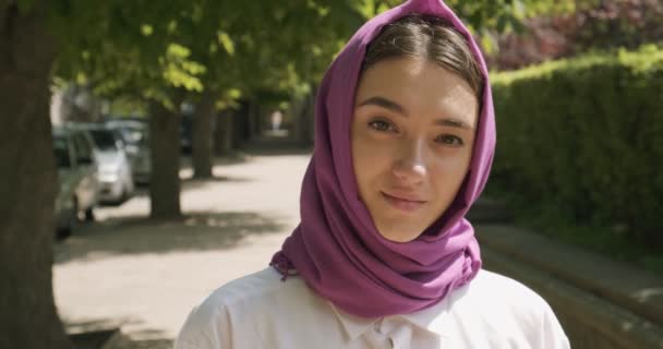 Hermosa mujer joven mirando a la cámara, con el tradicional pañuelo para la cabeza. Atractiva hembra en hijab — Vídeos de Stock