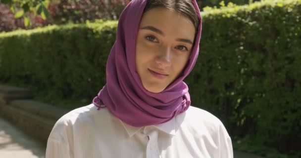 Hermosa mujer joven mirando a la cámara, con el tradicional pañuelo para la cabeza. Atractiva hembra en hijab — Vídeos de Stock