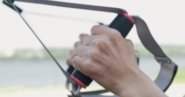 Güzel, genç bir kadın spor yapıyor. Açık havada spor kemerleriyle. Çekici bir kadın eğitimi. TRX. Kapat.