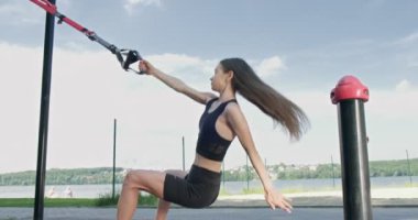 Güzel, genç bir kadın spor yapıyor. Açık havada spor kemerleriyle. Çekici Kadın Eğitimi