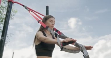 Güzel, genç bir kadın spor yapıyor. Açık havada spor kemerleriyle. Çekici Kadın Eğitimi