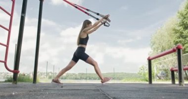 Güzel, genç bir kadın spor yapıyor. Açık havada spor kemerleriyle. Çekici Kadın Eğitimi