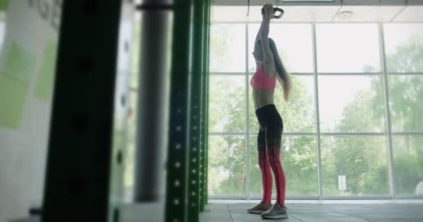 Hermosa joven hace entrenamiento con kettlebell en el gimnasio. Atractivo entrenamiento femenino — Vídeos de Stock