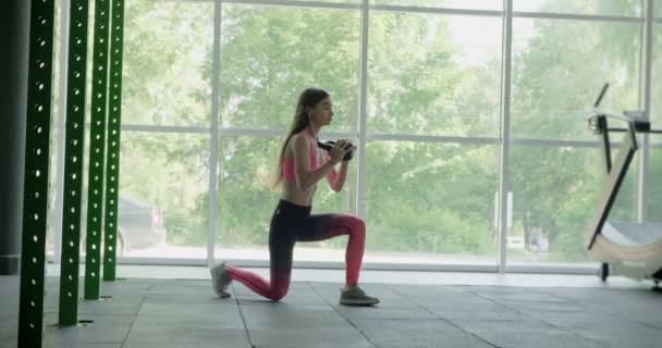 Красивая молодая женщина тренируется с гирями в спортзале. Привлекательная женская тренировка — стоковое видео