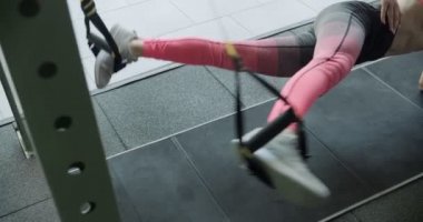 Güzel, genç bir kadın spor salonunda spor kemerleriyle antrenman yapıyor. Çekici Kadın Eğitimi