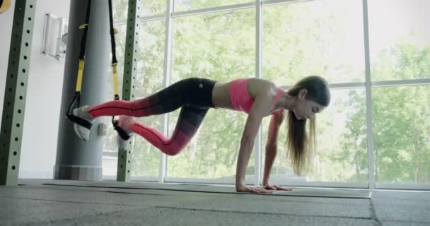 Mooie jonge vrouw traint met fitnessbandjes in de sportschool. Aantrekkelijke Vrouwelijke opleiding — Stockvideo