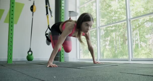 Hermosa mujer joven hace entrenamiento con correas de fitness en el gimnasio. Atractivo entrenamiento femenino — Vídeo de stock