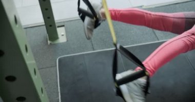 Güzel, genç bir kadın spor salonunda spor kemerleriyle antrenman yapıyor. Çekici Kadın Eğitimi