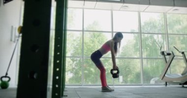 Güzel genç bir kadın spor salonunda kettlebell ile antrenman yapıyor. Çekici Kadın Eğitimi