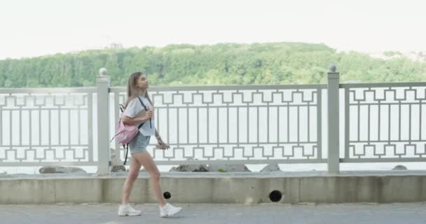 Gezinti güvertesinde gezen mutlu genç kadın turist. Çekici atletik kız spor eğitimine çantasıyla gider. Yaz gününün tadını çıkar — Stok video
