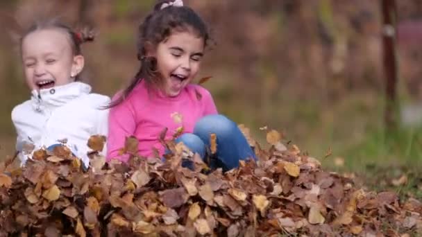 Deux petites filles heureuses avec des feuilles dans le parc. Feuillage jaune 