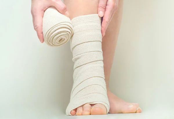 Woman applying elastic compression bandage as a thrombosis prevention after varicose surgery — Stock Photo, Image