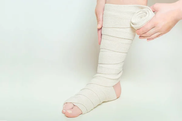 Woman applying elastic compression bandage as a thrombosis prevention after varicose surgery