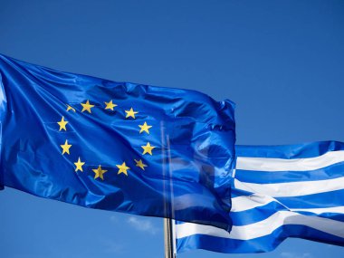 Mavi gökyüzünde sallayarak Yunan ve Avrupa Birliği bayrakları