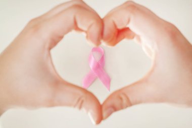 Pembe bir kurdele, meme kanseri bilinçlendirme kavramı ile bir kalp şekil verme eller