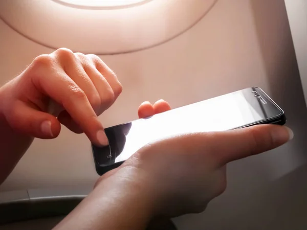 Žena ruka pomocí chytrého telefonu v letadle — Stock fotografie