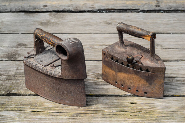 Старые антикварные утюги на старинном деревянном фоне