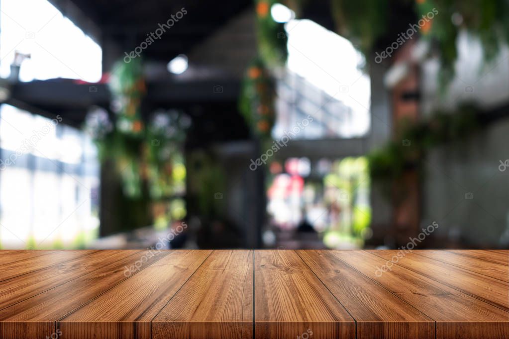 Empty wooden table top with blurred coffee shop or restaurant interior background. 