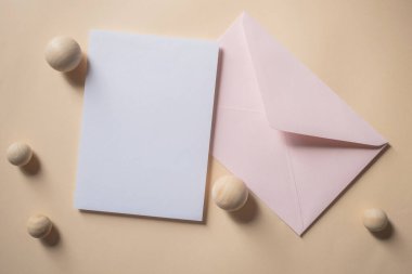 Boş beyaz tebrik kartı ya da bej arka planda pembe zarflı davetiye kartı. Sunum uydurma. Kopyalama alanı olan asgari modern biçim.