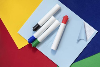 Defter ve keçeli kalemler renkli parlak kağıt, parlak arka plan. Üstten görünüm. Başlayan okul, yaratık, eğitim kavramı